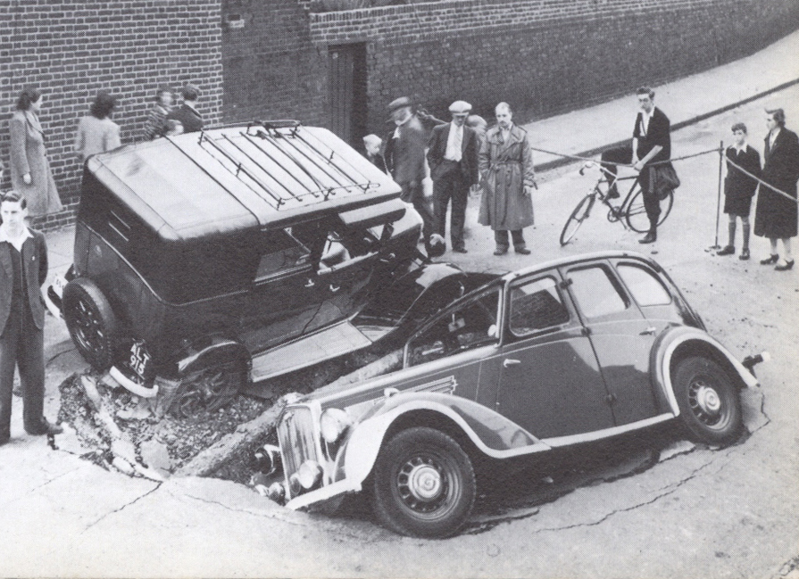 A Wolseley 14 and Austin taxi meet in a bomb crater